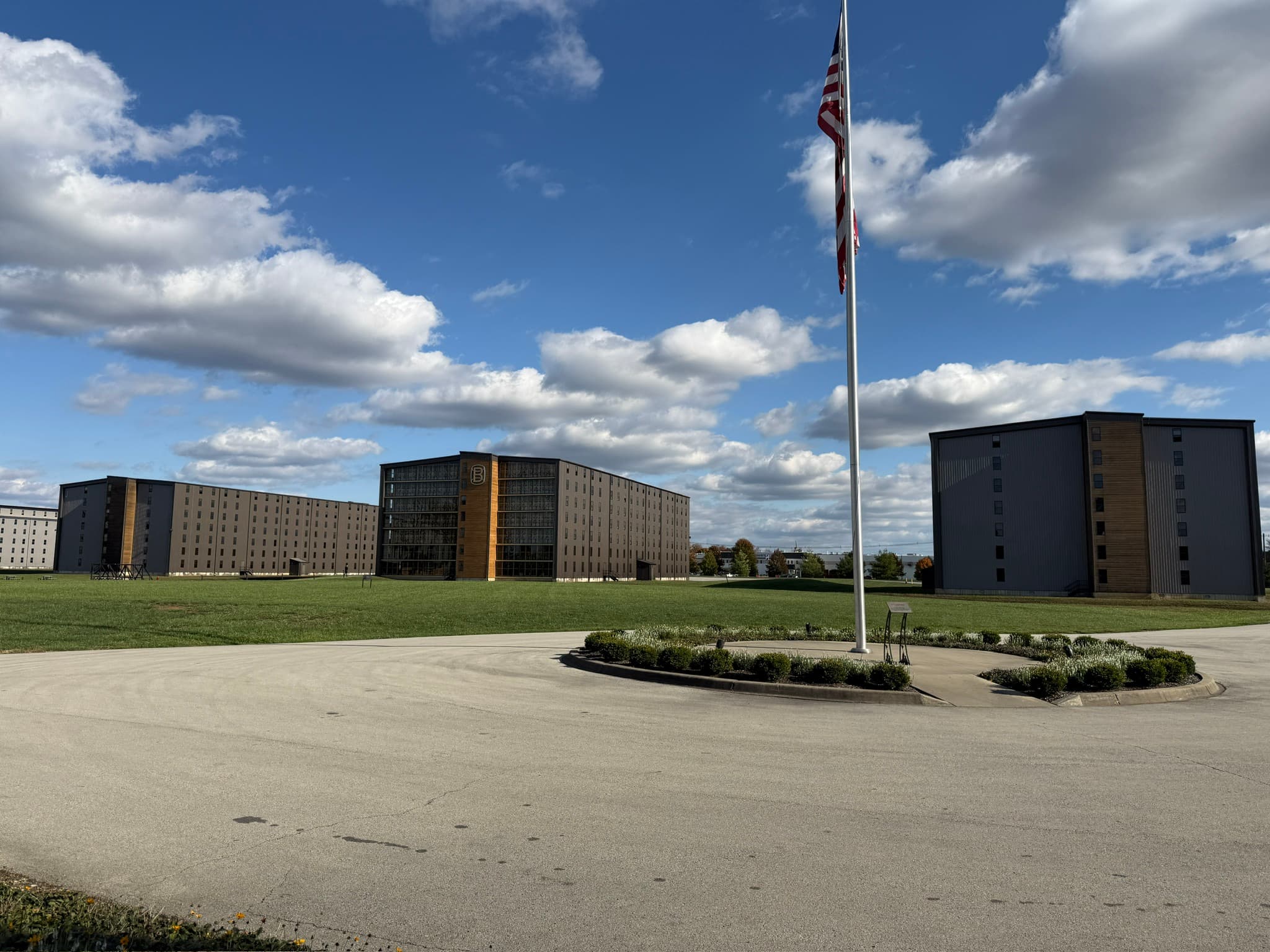 The rickhouses at Bardstown Bourbon Company under a blue Kentucky sky, with the American flag flying over the grounds